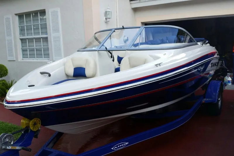 The Image of 2014 Tahoe Q4 boat on trailer, parked outside a house. - 0