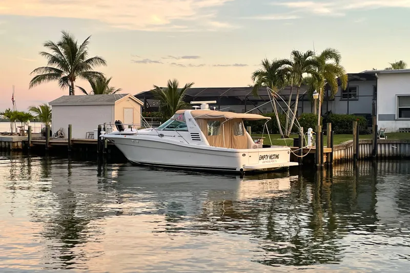 Slide: The Image of 1997 Sea Ray 370 Express Cruiser docked by palm trees at sunset. - 2