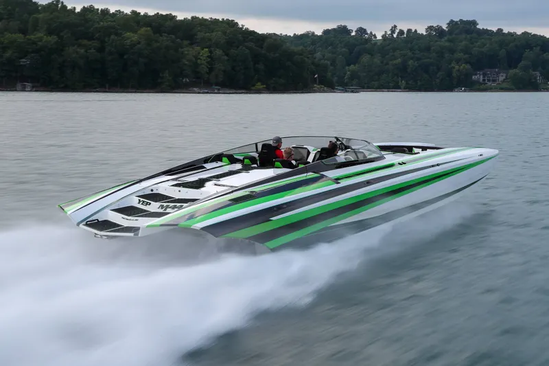 Slide: The Image of 2022 Daves Custom Boats M-44 speeding on a lake with lush forest backdrop. - 2