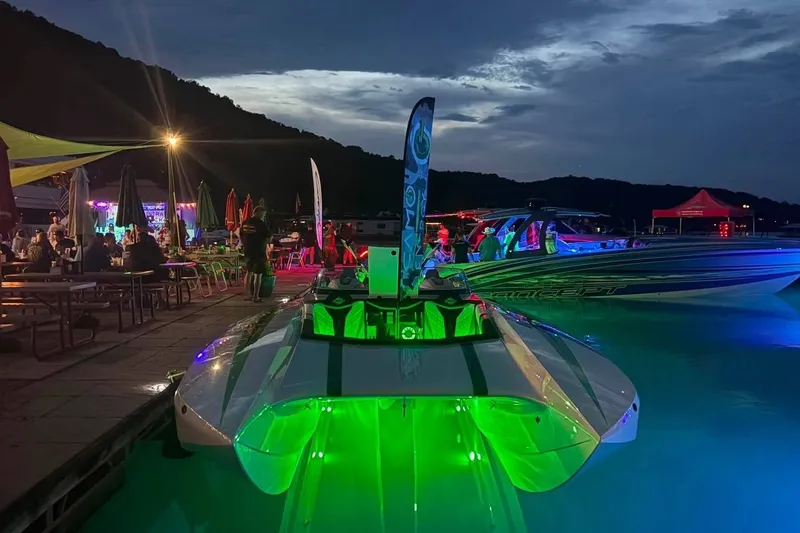 Slide: The Image of 2022 Daves Custom Boats M-44 illuminated at night by a lively waterfront gathering. - 13