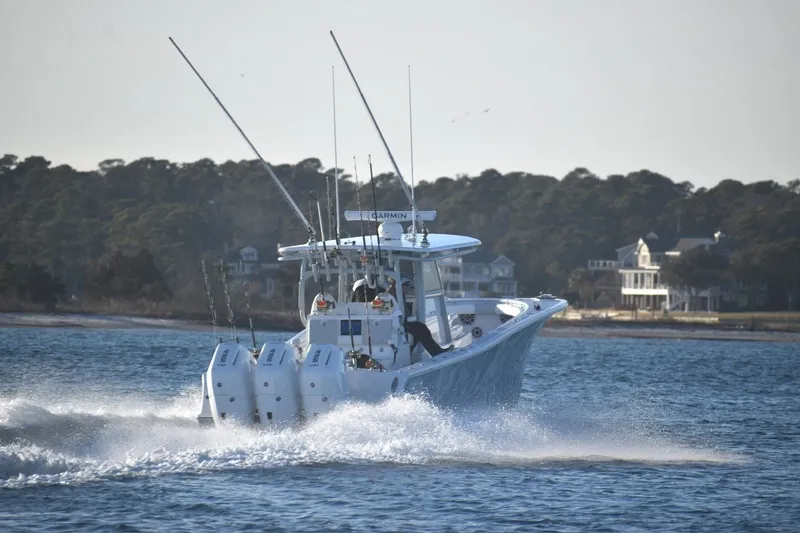 Slide: The Image of 2026 Onslow Bay 37 Tournament Edition boat cruising on water near shoreline homes. - 13