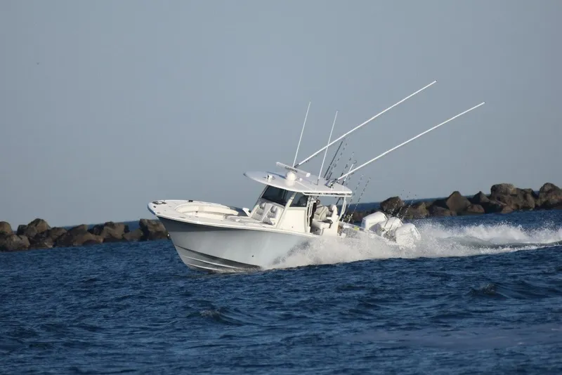 Slide: The Image of 2026 Onslow Bay 37 Tournament Edition boat cruising on open water near rocky shoreline. - 20
