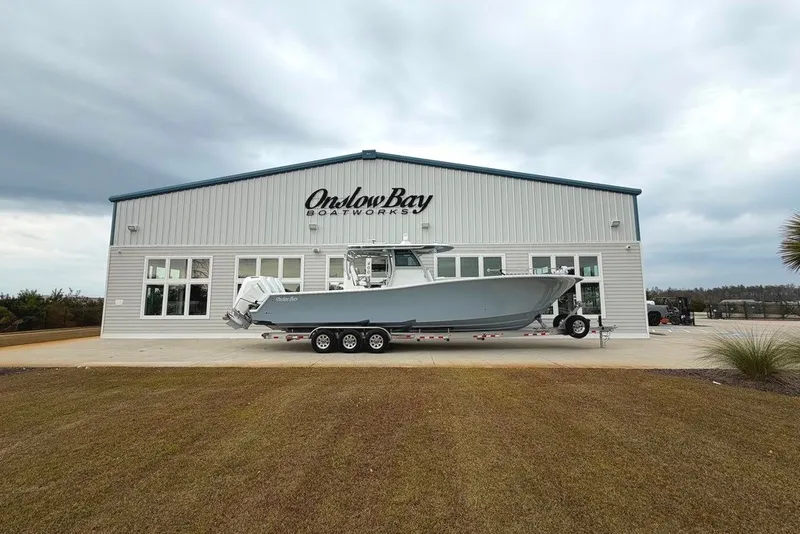 Slide: The Image of Onslow Bay 37 Tournament Edition 2026 boat outside showroom, cloudy sky backdrop. - 110