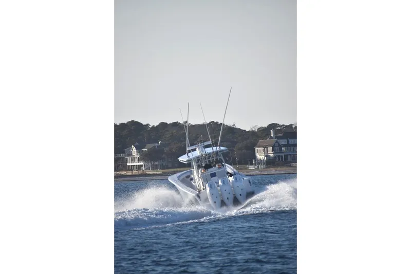 Slide: The Image of Onslow Bay 37 Tournament Edition 2026 speeding on water near coastal homes. - 14