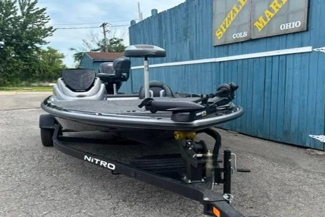 Slide: The Image of 2026 Nitro Z17 boat on trailer, parked outdoors near blue fence. - 2