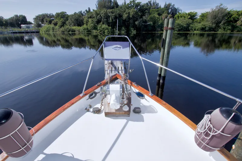 Slide: The Image of Bow view of 1980 Kadey-Krogen 42 yacht on calm water, surrounded by lush greenery. - 28