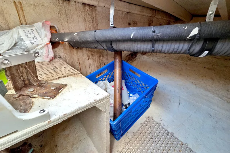 Slide: The Image of Storage area in a 1980 Kadey-Krogen 42 boat with pipes and a blue crate. - 102