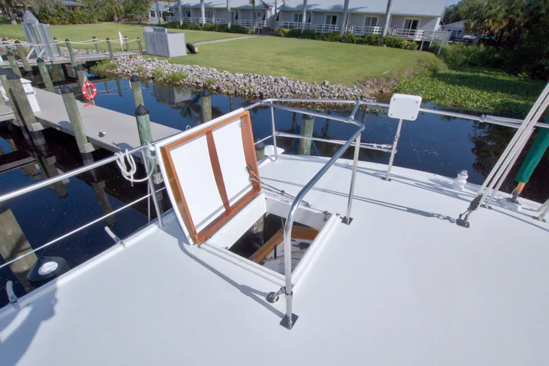 Slide: The Image of Kadey-Krogen 42 yacht deck with open hatch, docked near grassy shoreline, 1980 model. - 21