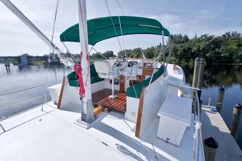 Slide: The Image of 1980 Kadey-Krogen 42 yacht with green canopy docked by a serene river. - 13