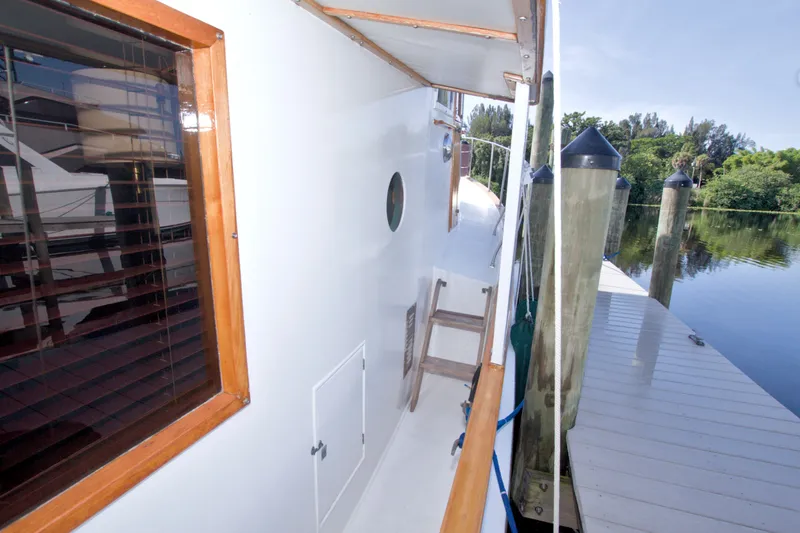 Slide: The Image of 1980 Kadey-Krogen 42 yacht docked, showcasing side deck and wooden window frame. - 35