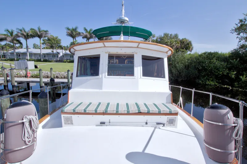 Slide: The Image of 1980 Kadey-Krogen 42 yacht docked, featuring a spacious deck and lush surroundings. - 30