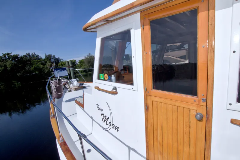 Slide: The Image of 1980 Kadey-Krogen 42 yacht with wooden door, docked by a serene river. - 26