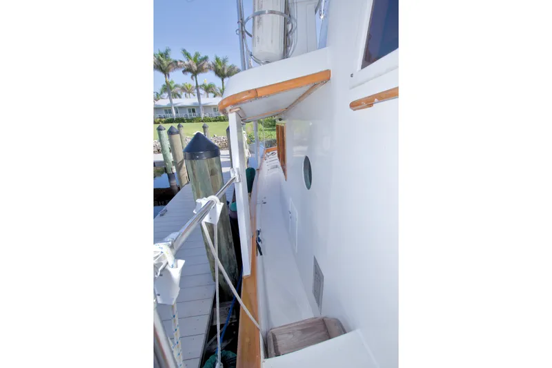 Slide: The Image of Side deck of 1980 Kadey-Krogen 42 yacht docked, featuring white exterior and wooden accents. - 34
