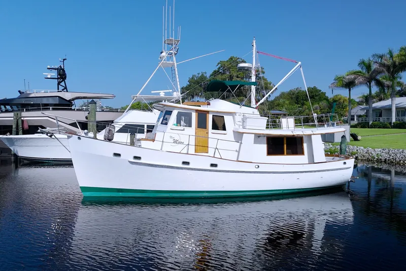 Slide: The Image of 1980 Kadey-Krogen 42 yacht docked on calm water, surrounded by lush greenery. - 104