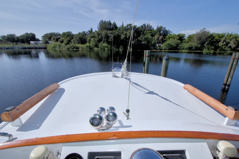 Slide: The Image of Bow view of 1980 Kadey-Krogen 42 yacht on calm water with lush greenery. - 17