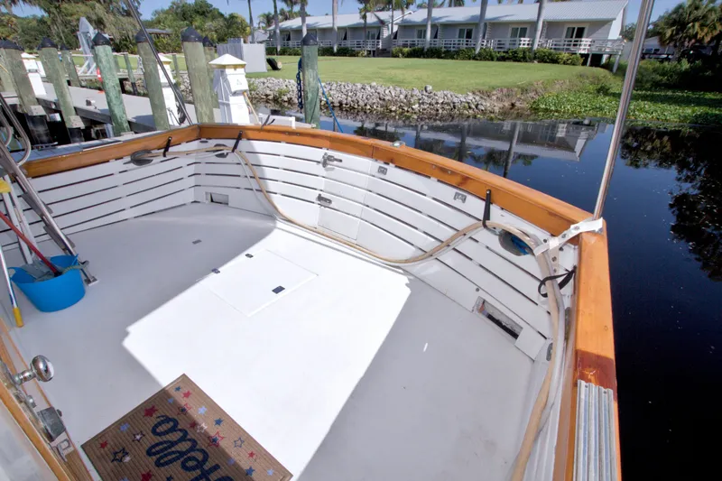 Slide: The Image of Kadey-Krogen 42 boat deck, 1980 model, docked by a serene waterfront with lush greenery. - 99