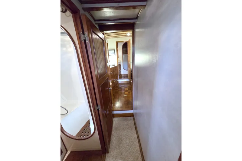 Slide: The Image of Narrow hallway inside 1980 Kadey-Krogen 42 yacht, featuring wooden doors and flooring. - 68