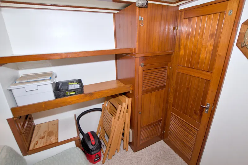 Slide: The Image of Wooden storage area inside a 1980 Kadey-Krogen 42 boat, featuring shelves and a vacuum. - 63