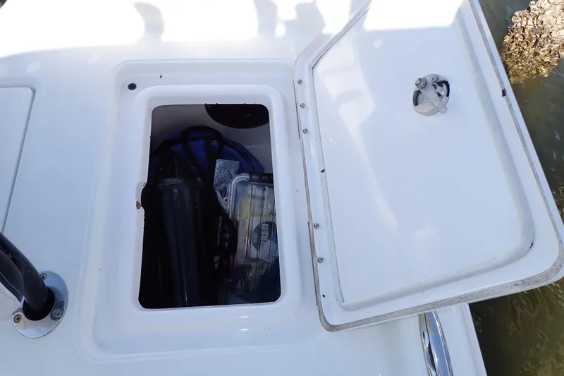 Slide: The Image of Open storage compartment on a 2015 Blue Wave 2400 PureBay boat, containing various gear. - 72