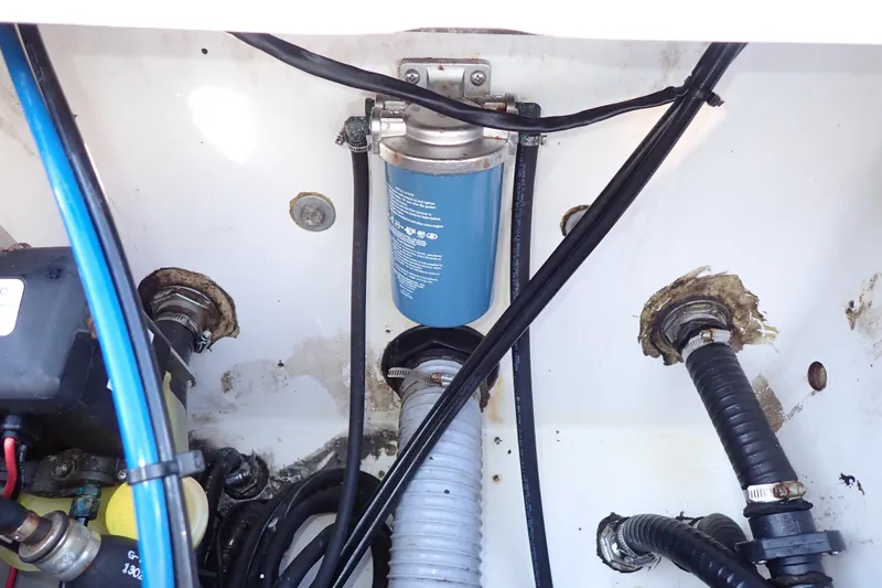 Slide: The Image of Engine compartment of a 2015 Blue Wave 2400 PureBay boat, showing hoses and a filter. - 77