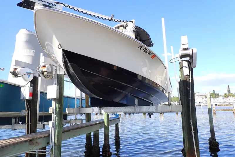 Slide: The Image of 2015 Blue Wave 2400 PureBay boat on lift at marina, clear sky background. - 104