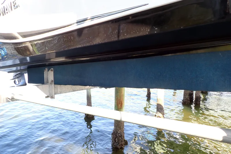Slide: The Image of 2015 Blue Wave 2400 PureBay boat on lift above water, showing hull and support beams. - 96