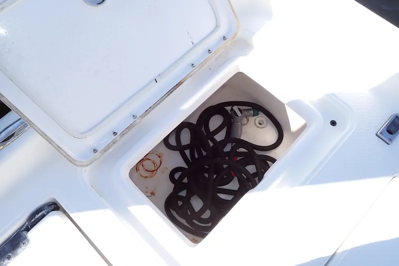 Slide: The Image of Open storage compartment on 2015 Blue Wave 2400 PureBay boat with coiled hose inside. - 79