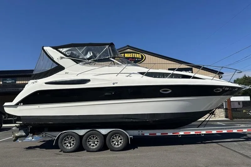 The Image of 2004 Bayliner 3055 Ciera Sunbridge on trailer, parked outside a building under clear blue sky. - 1
