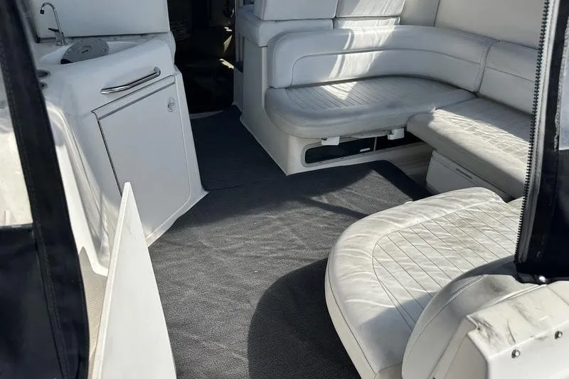 Slide: The Image of Interior of 2004 Bayliner 3055 Ciera Sunbridge with white seating and compact kitchenette. - 14