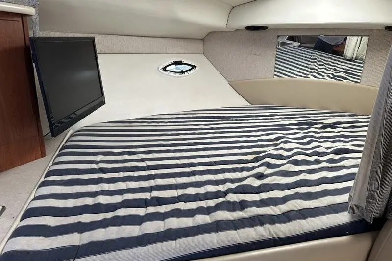 Slide: The Image of 2004 Bayliner 3055 Ciera Sunbridge cabin with striped bedding and wall-mounted TV. - 32