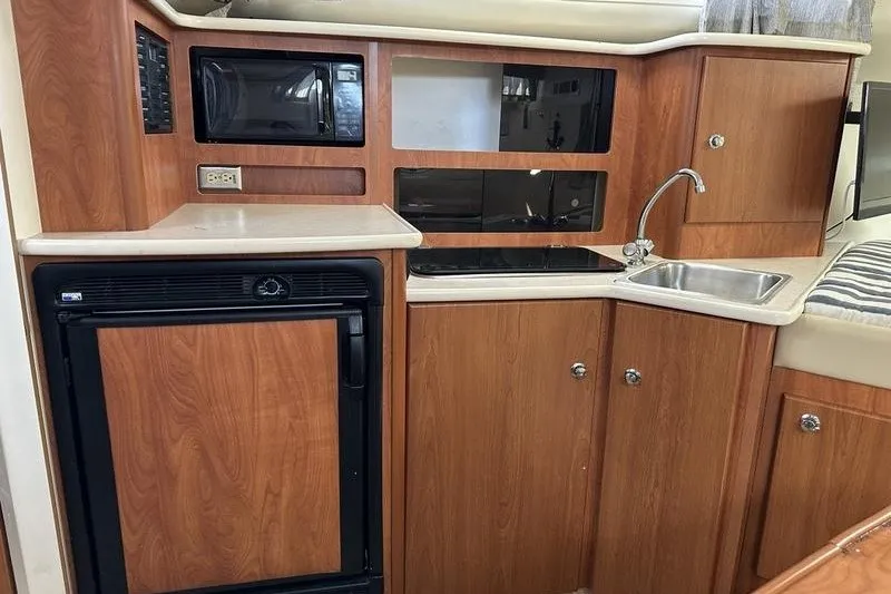 Slide: The Image of 2004 Bayliner 3055 Ciera Sunbridge kitchen with wood cabinets, sink, and appliances. - 26