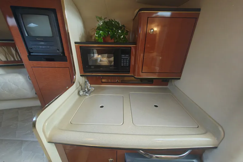 Slide: The Image of 2002 Sea Ray Sundancer 280 cabin kitchen with sink, microwave, and TV. - 12