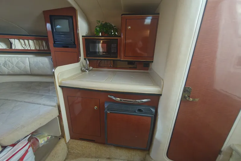 Slide: The Image of 2002 Sea Ray Sundancer 280 interior with kitchenette, featuring sink, microwave, and storage cabinets. - 11