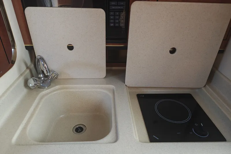 Slide: The Image of 2002 Sea Ray Sundancer 280 galley with sink and stovetop, featuring beige countertops. - 13