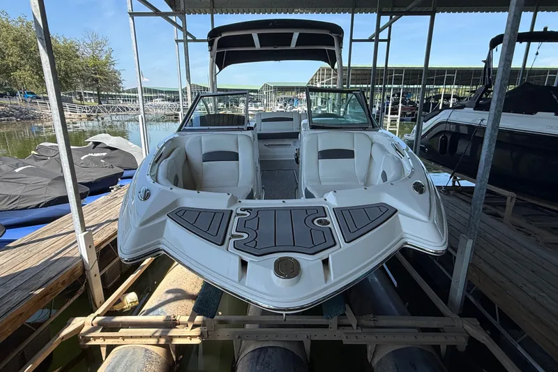 Slide: The Image of 2014 Chaparral 224 Sunesta boat docked in a marina, featuring spacious seating and sleek design. - 1