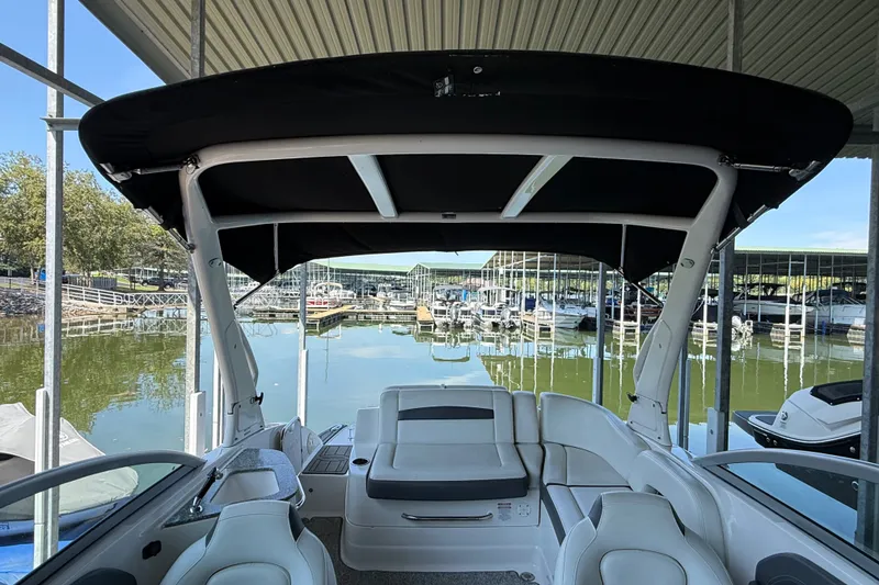 Slide: The Image of 2014 Chaparral 224 Sunesta boat interior at marina, featuring seating and canopy. - 20