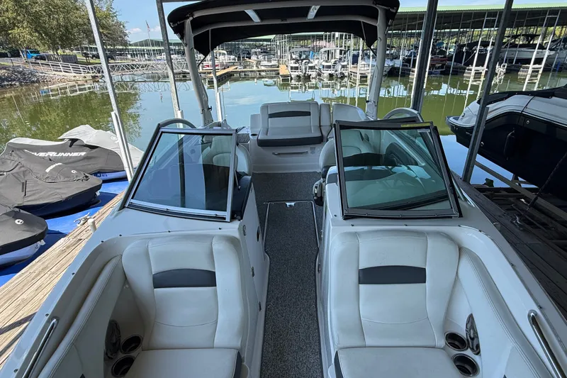 Slide: The Image of 2014 Chaparral 224 Sunesta boat interior at marina, featuring white seating and open deck. - 22