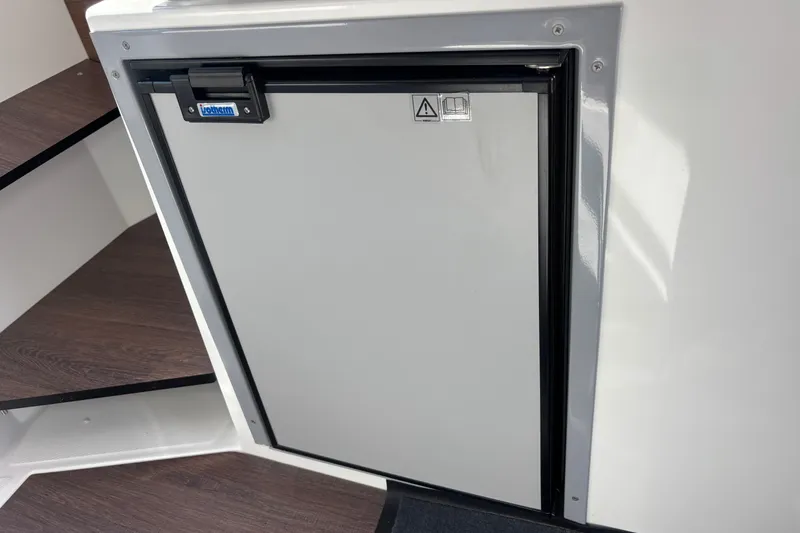 Slide: The Image of Compact fridge on 2025 Beneteau Antares 8 boat interior, near wooden steps. - 14