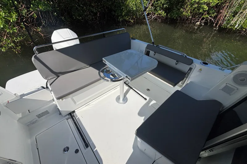 Slide: The Image of 2025 Beneteau Antares 8 boat interior with seating and table, surrounded by water and greenery. - 23