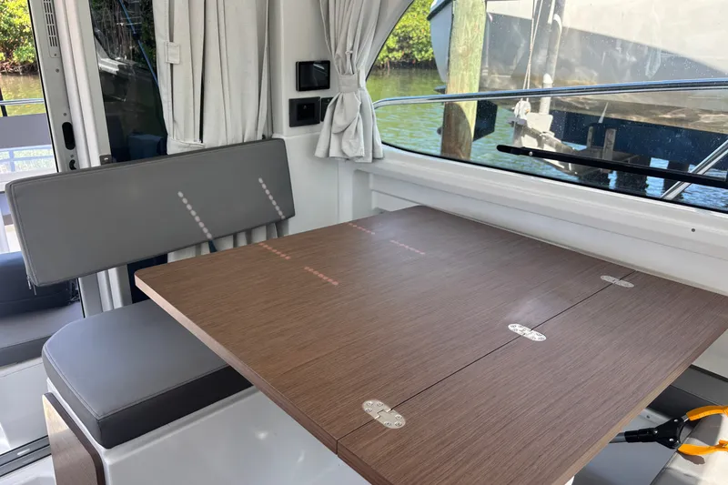 Slide: The Image of Interior of 2025 Beneteau Antares 8 with foldable wooden table and gray seating. - 25