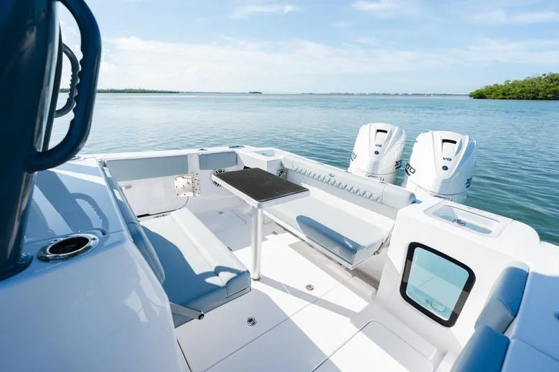 Slide: The Image of 2027 Sportsman Open 232 Center Console boat interior with seating and twin engines on a calm sea. - 2
