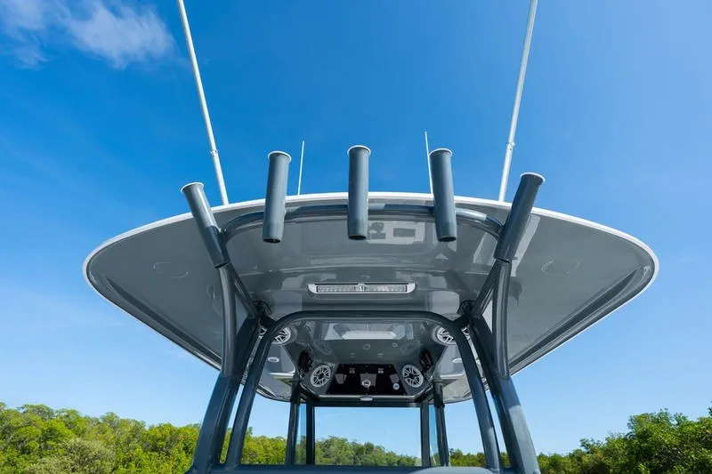 Slide: The Image of 2027 Sportsman Open 232 Center Console boat with rod holders and speakers, under clear blue sky. - 32