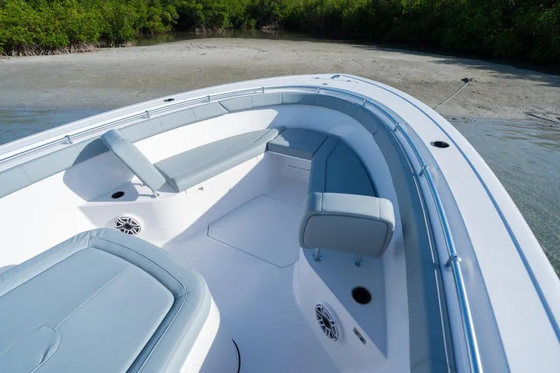 Slide: The Image of 2027 Sportsman Open 232 Center Console boat with cushioned seating, docked near a sandy shore. - 6
