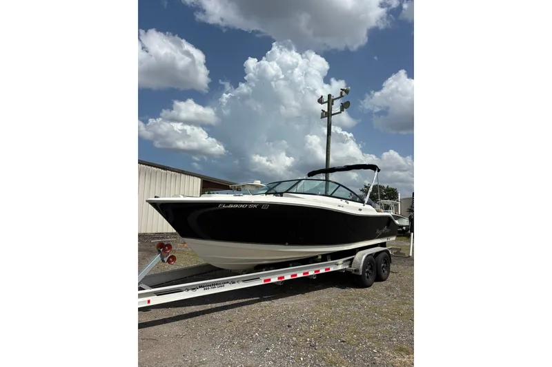The Image of 2019 NauticStar 2302 Legacy Dual Console boat on trailer under cloudy sky. - 0