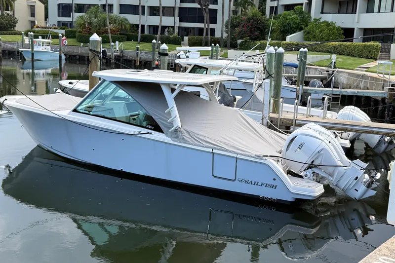 The Image of 2026 Sailfish 316 DC boat docked in marina, covered and equipped with twin outboard engines. - 0
