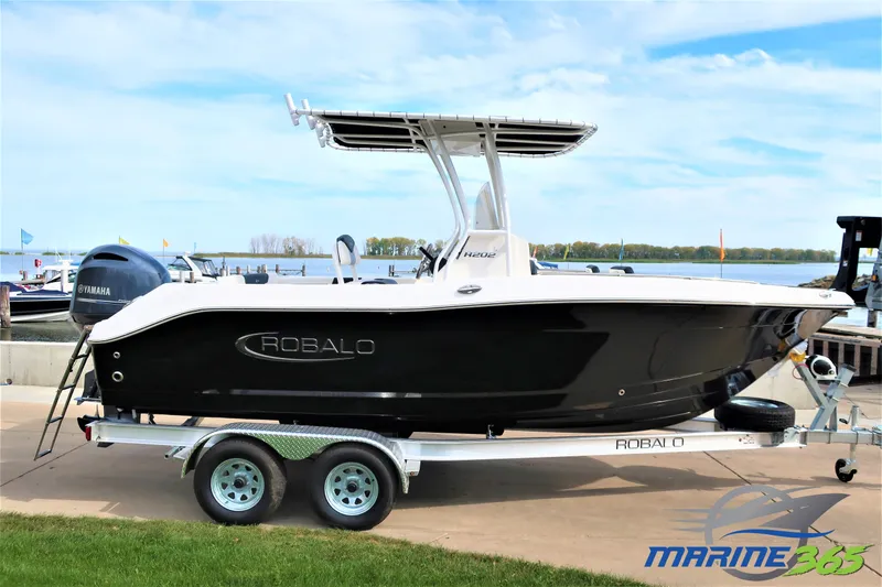 The Image of 2023 Robalo R202 Explorer boat on trailer by waterfront, featuring sleek black design. - 1