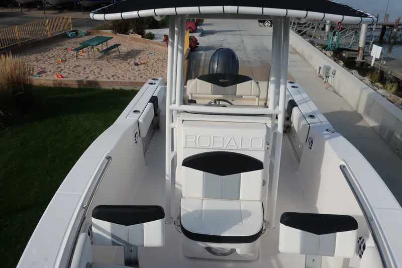 Slide: The Image of 2023 Robalo R202 Explorer boat with seating and console, docked near a sandy play area. - 11