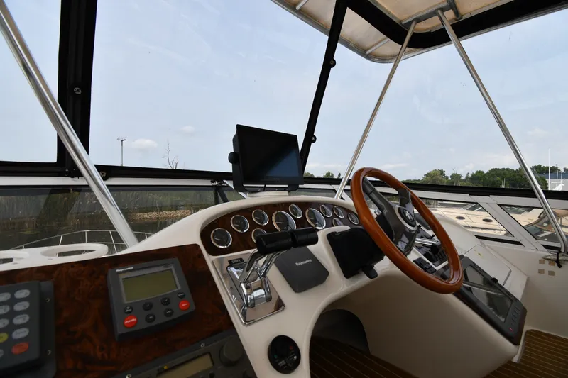 Slide: The Image of 1998 Sea Ray 400 Sedan Bridge helm with wooden steering wheel and navigation instruments. - 20