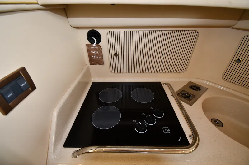 Slide: The Image of 1998 Sea Ray 400 Sedan Bridge kitchen with electric stove and beige cabinetry. - 47