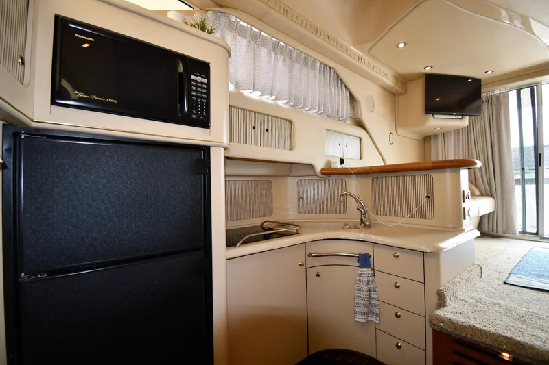 Slide: The Image of 1998 Sea Ray 400 Sedan Bridge interior with kitchenette, featuring microwave, fridge, and sink. - 45